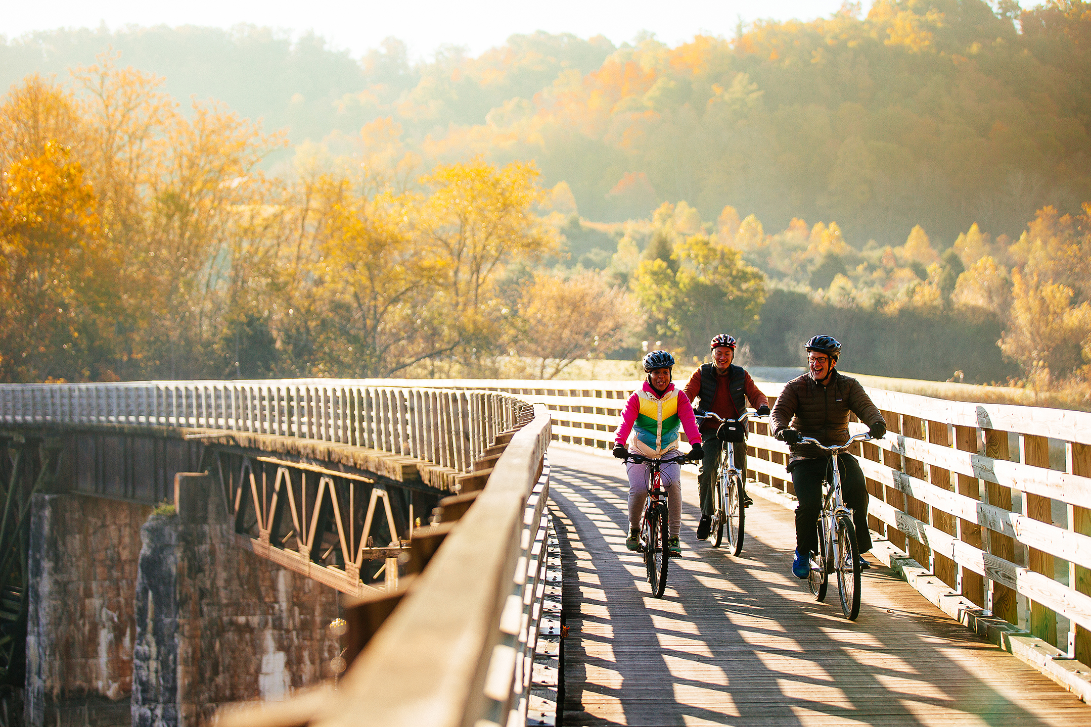 A family riding bicycles along an elevated platform with mountains in the background