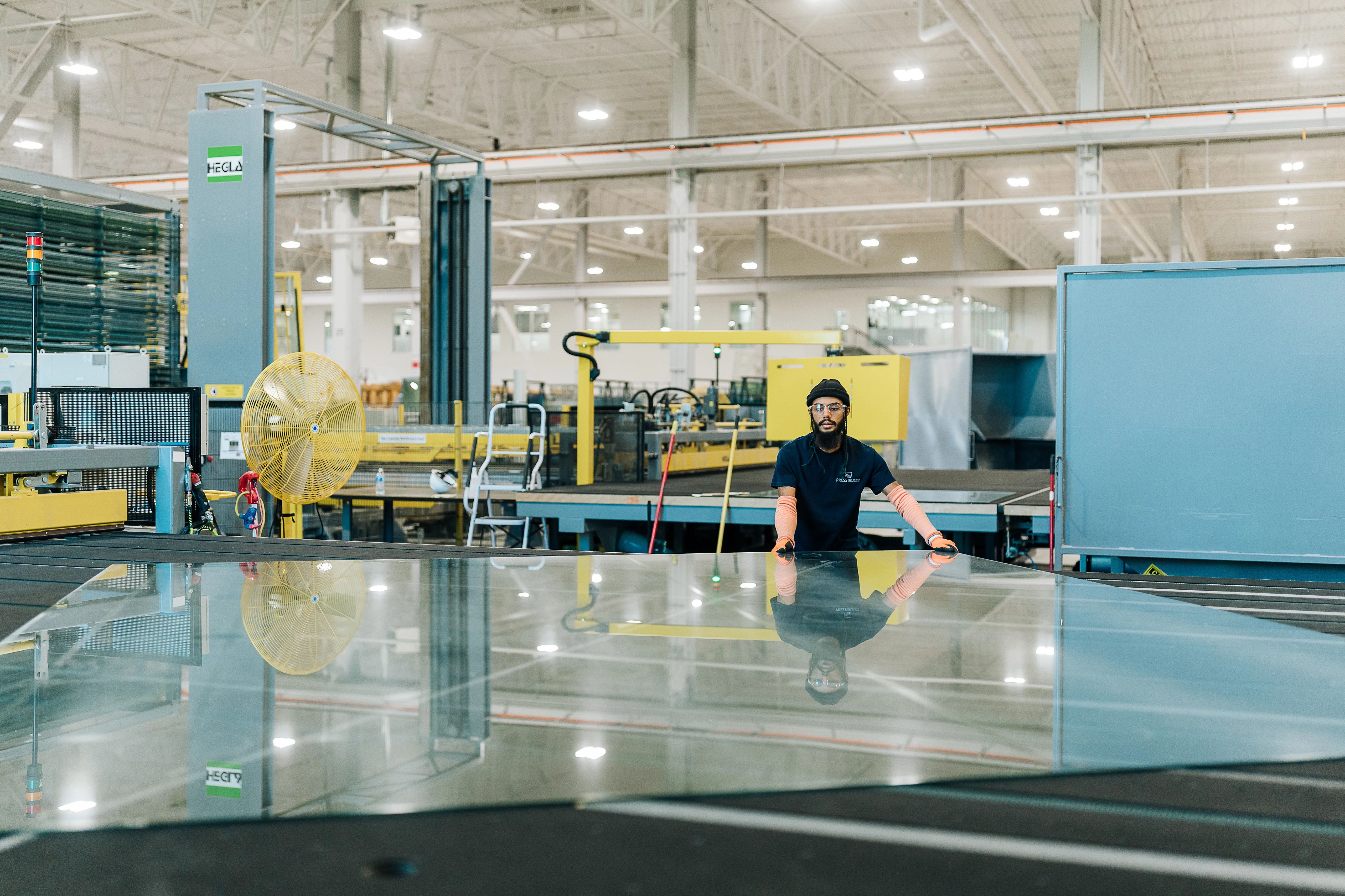 Man in Press Glass manufacturing facility working on sheet of glass.