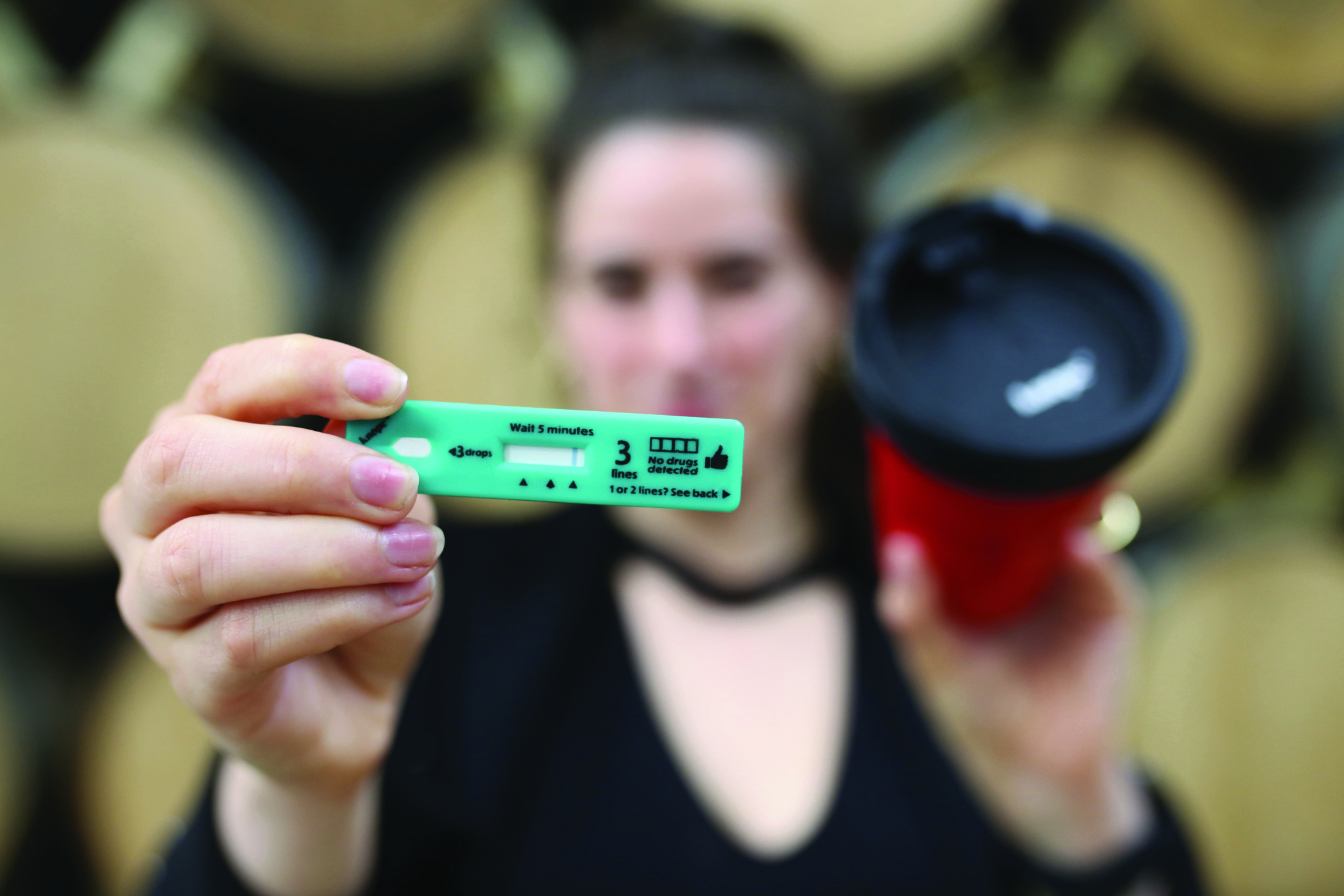 Women holding a drink drug test and cup