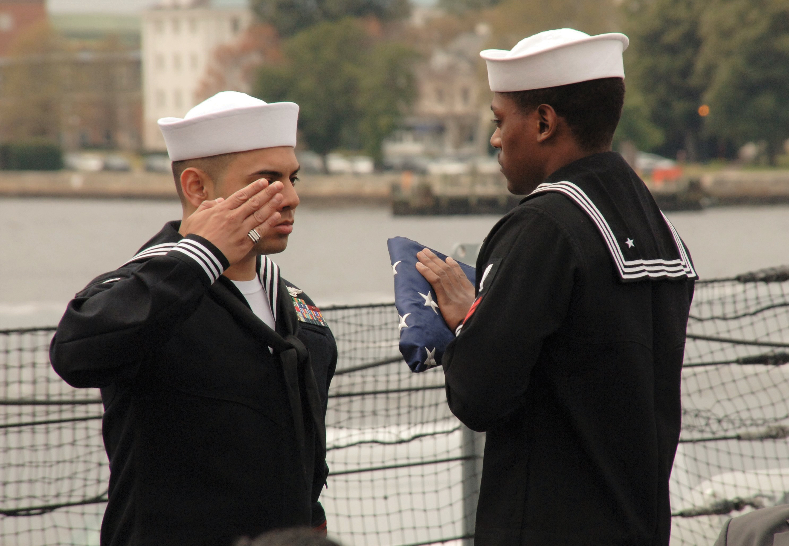 One sailor in uniform saluting another sailor