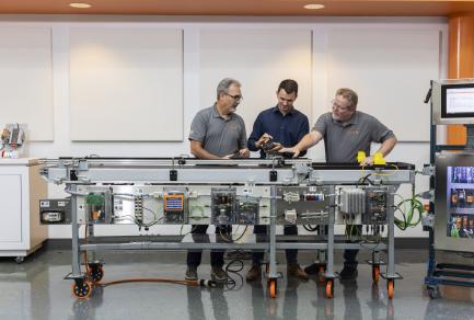 Three Weidmuller employees working on a conveyor belt
