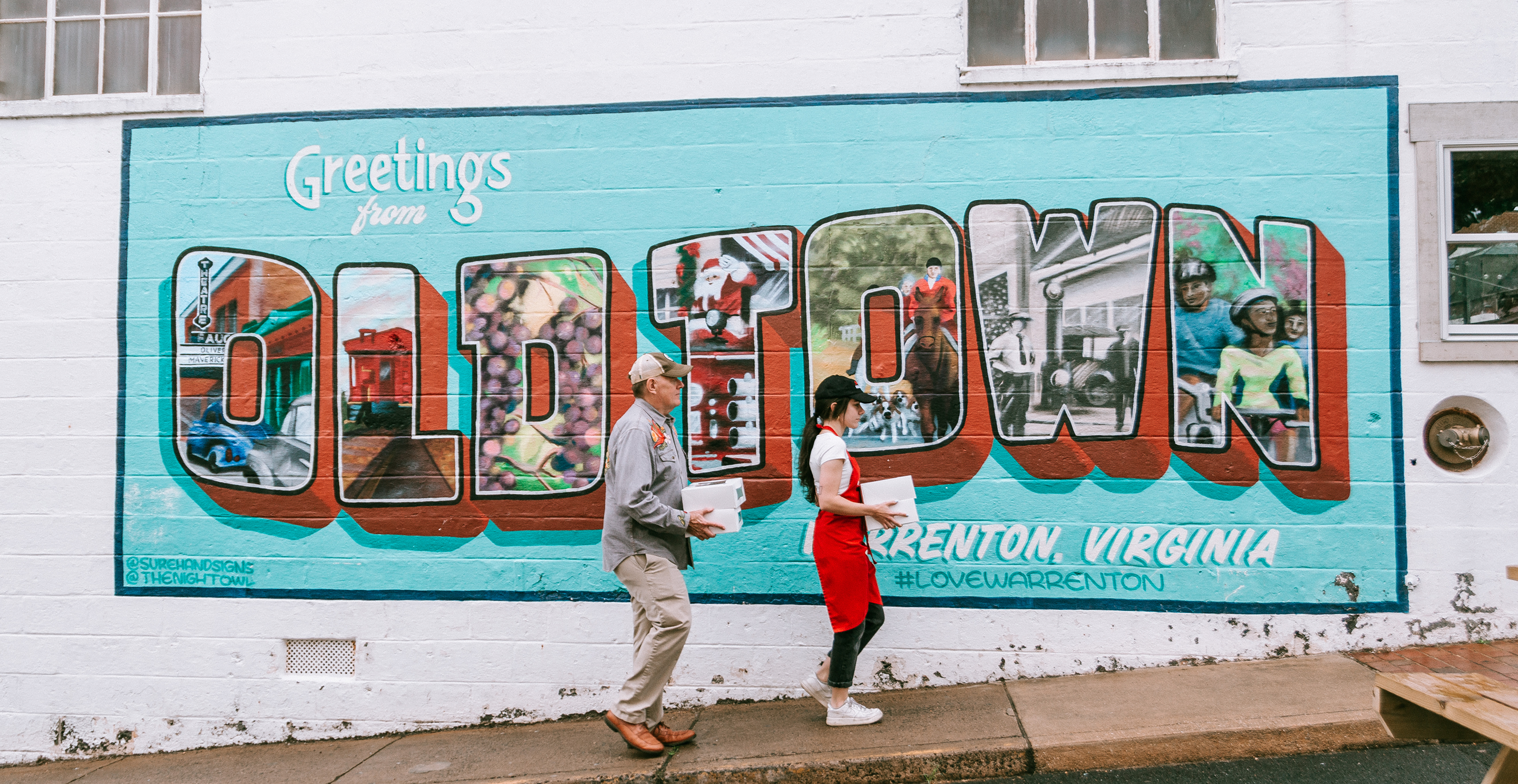 Workers carrying goods in front of a mural that says Oldtown