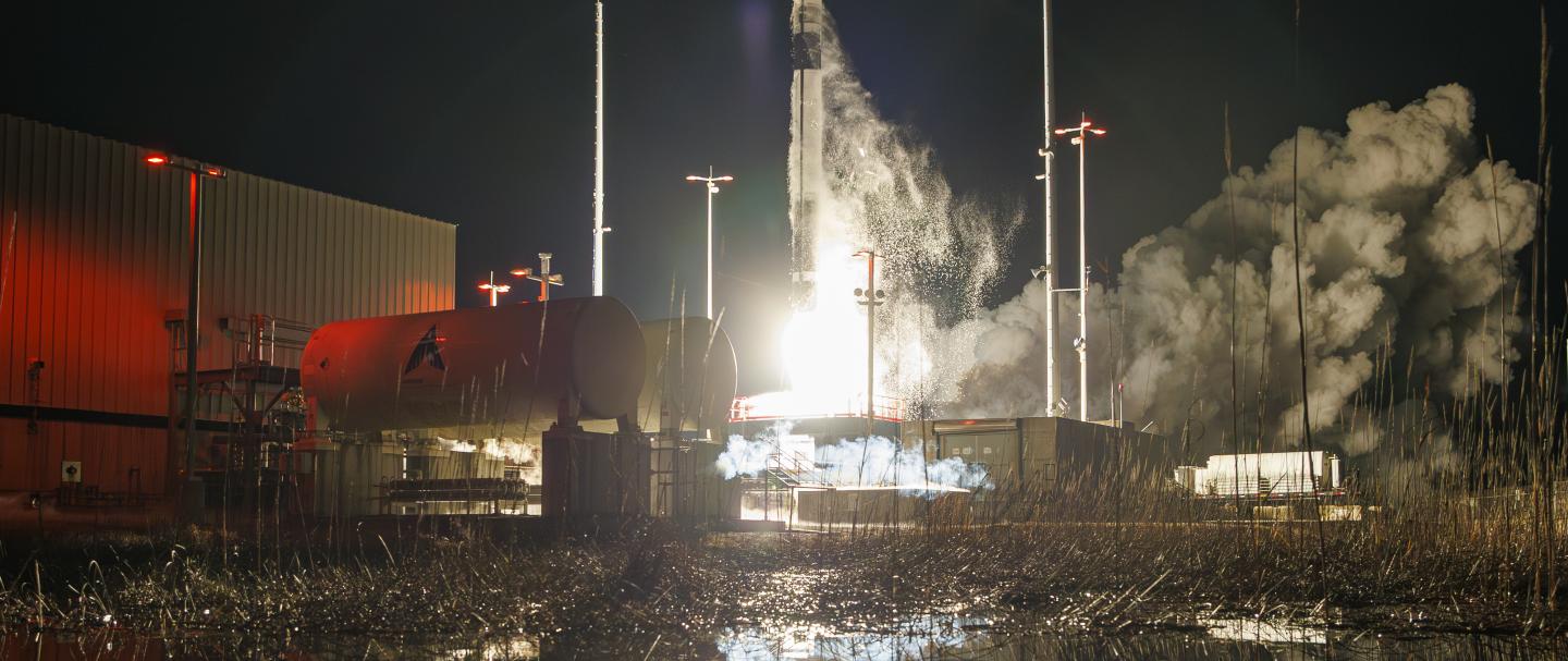 A rocket taking off from a launch pad at night