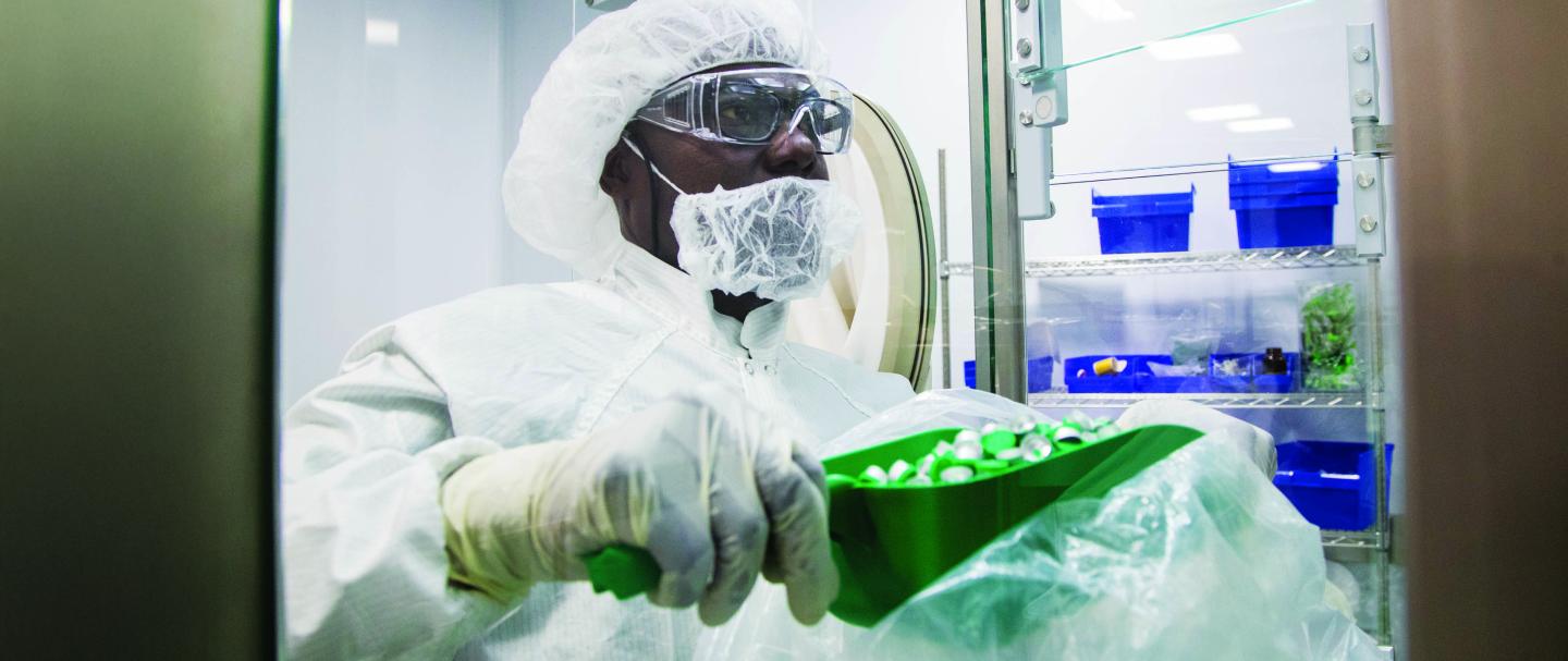 A man in protective gear scooping items into a container