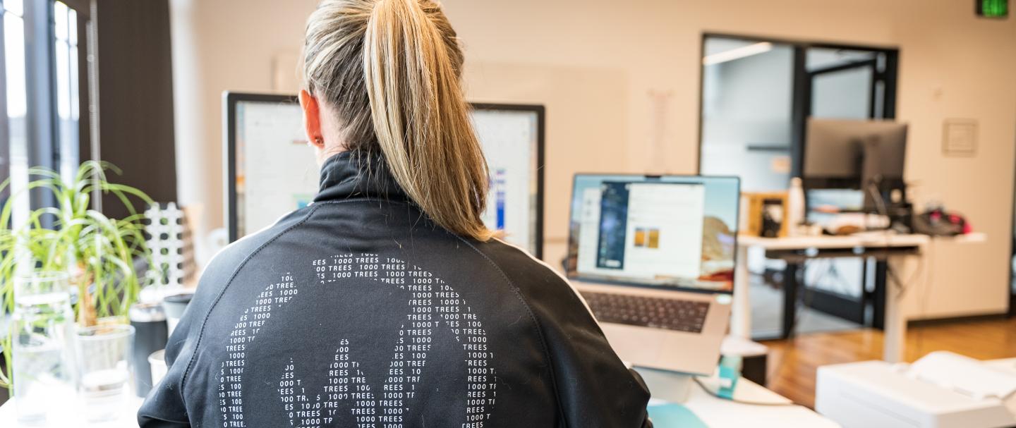 A woman typing on a computer with her back to the camera