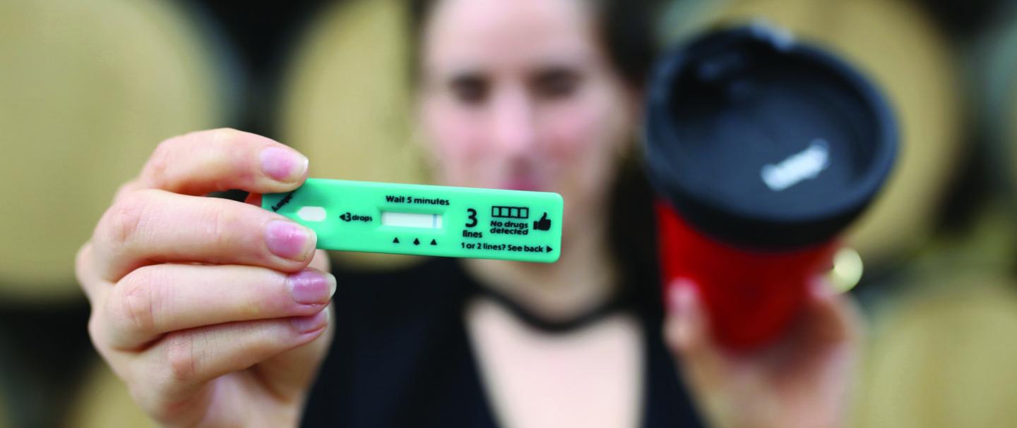 Women holding a drink drug test and cup