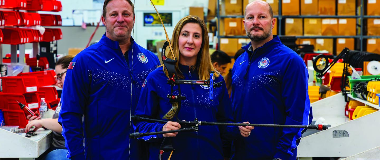 Three T.R.U. ball employees holding a bow and arrow 