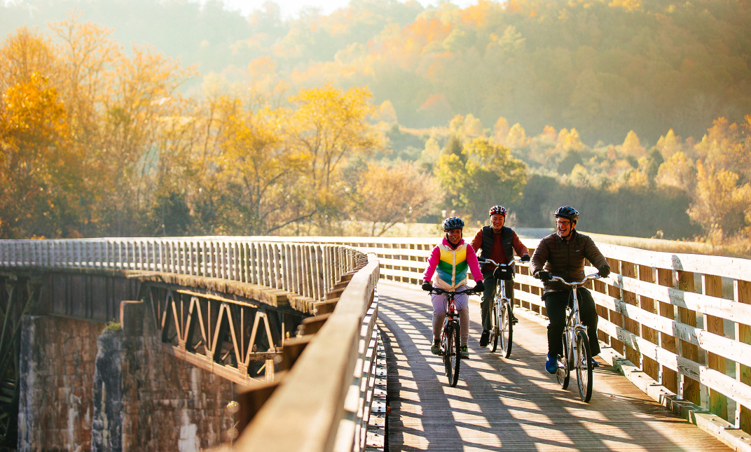 A family riding bicycles along an elevated platform with mountains in the background