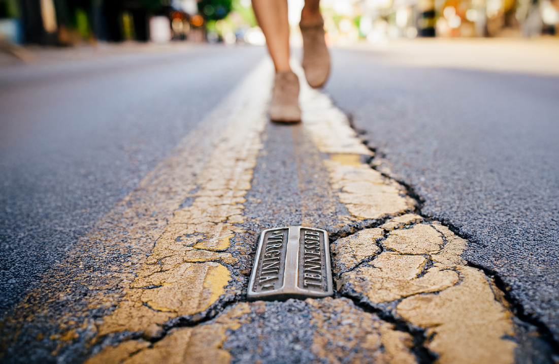Person walking across the Virginia-Tennessee state line marker