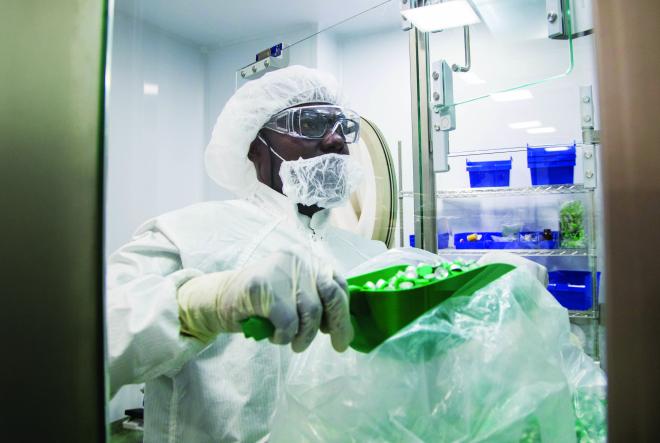 A man in protective gear scooping items into a container